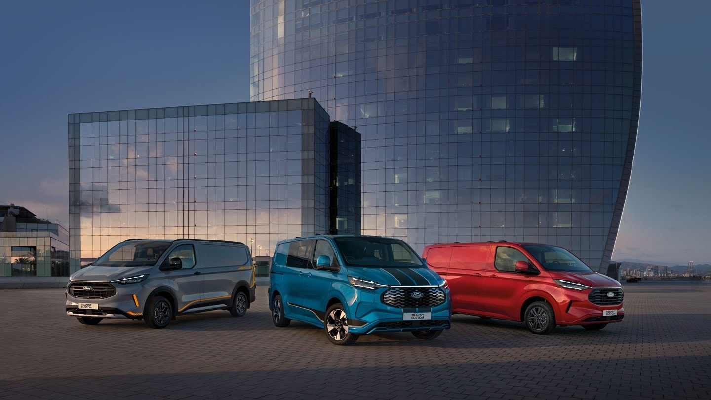 Alle Transit Custom-modeller parkert foran en moderne bygning.