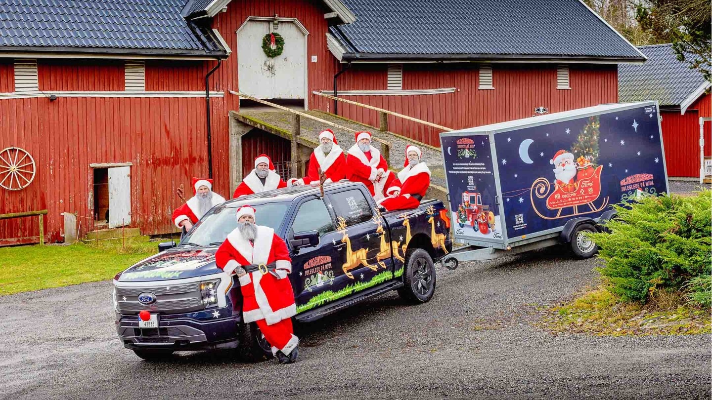 Skjeggnissene står rundt F-150 Lightning som er parkert forane en låve.