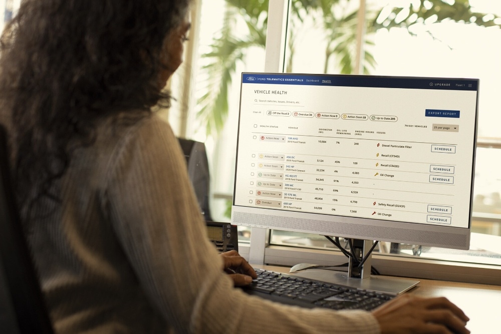 En person sitter ved et skrivebord og bruker en datamaskin som viser en Ford Telematics-skjerm.