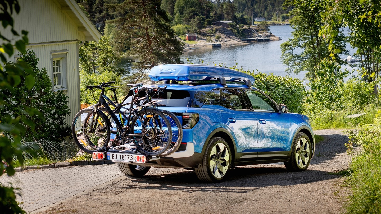 Blå helelektrisk Ford Explorer med takboks og sykler på hengerfestestativ. 