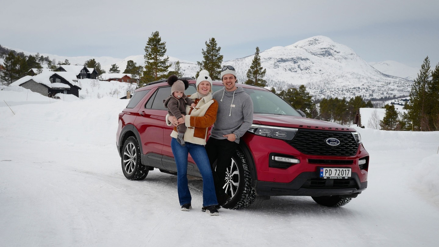 Happy family next to red Explorer