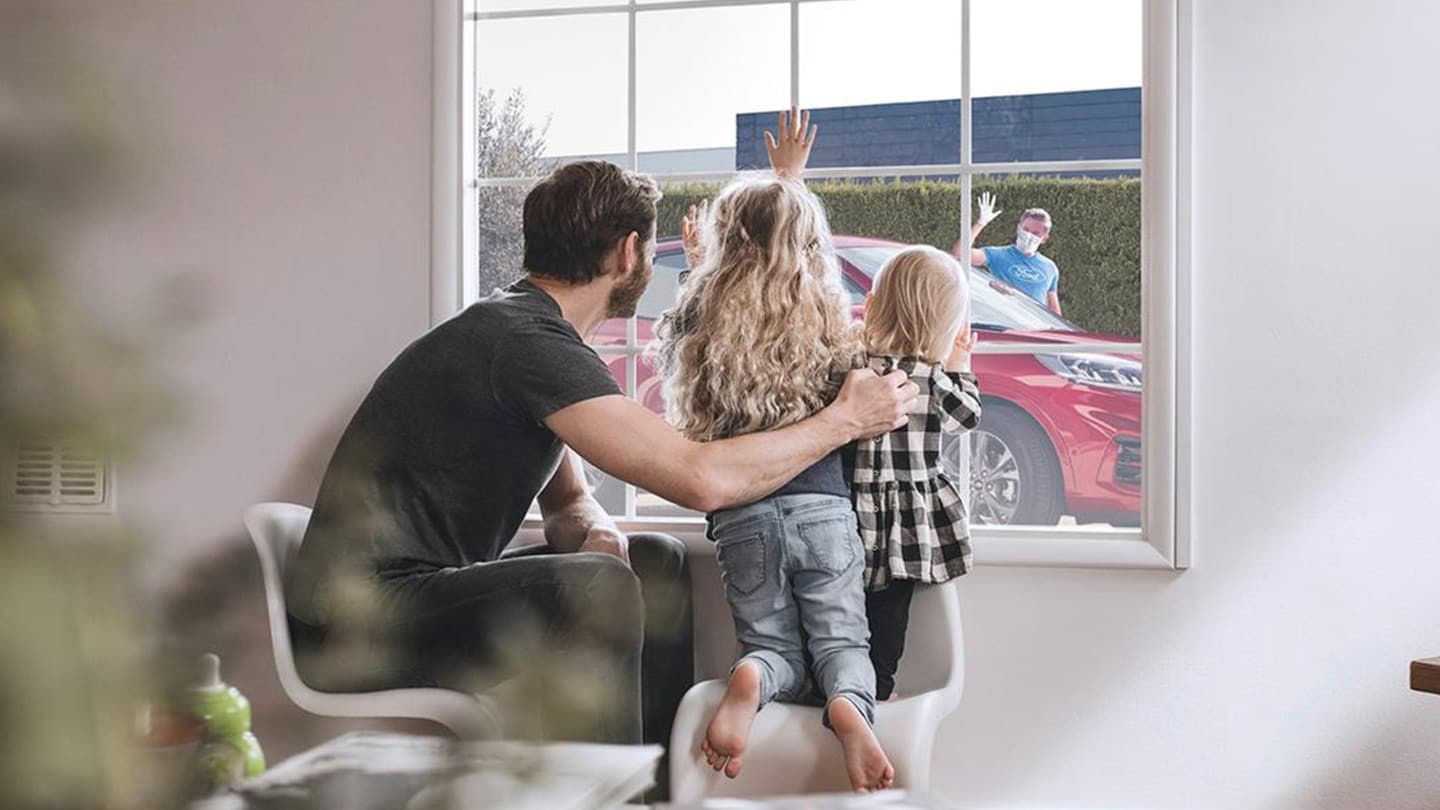 Family looking from a window on a red Ford Kuga