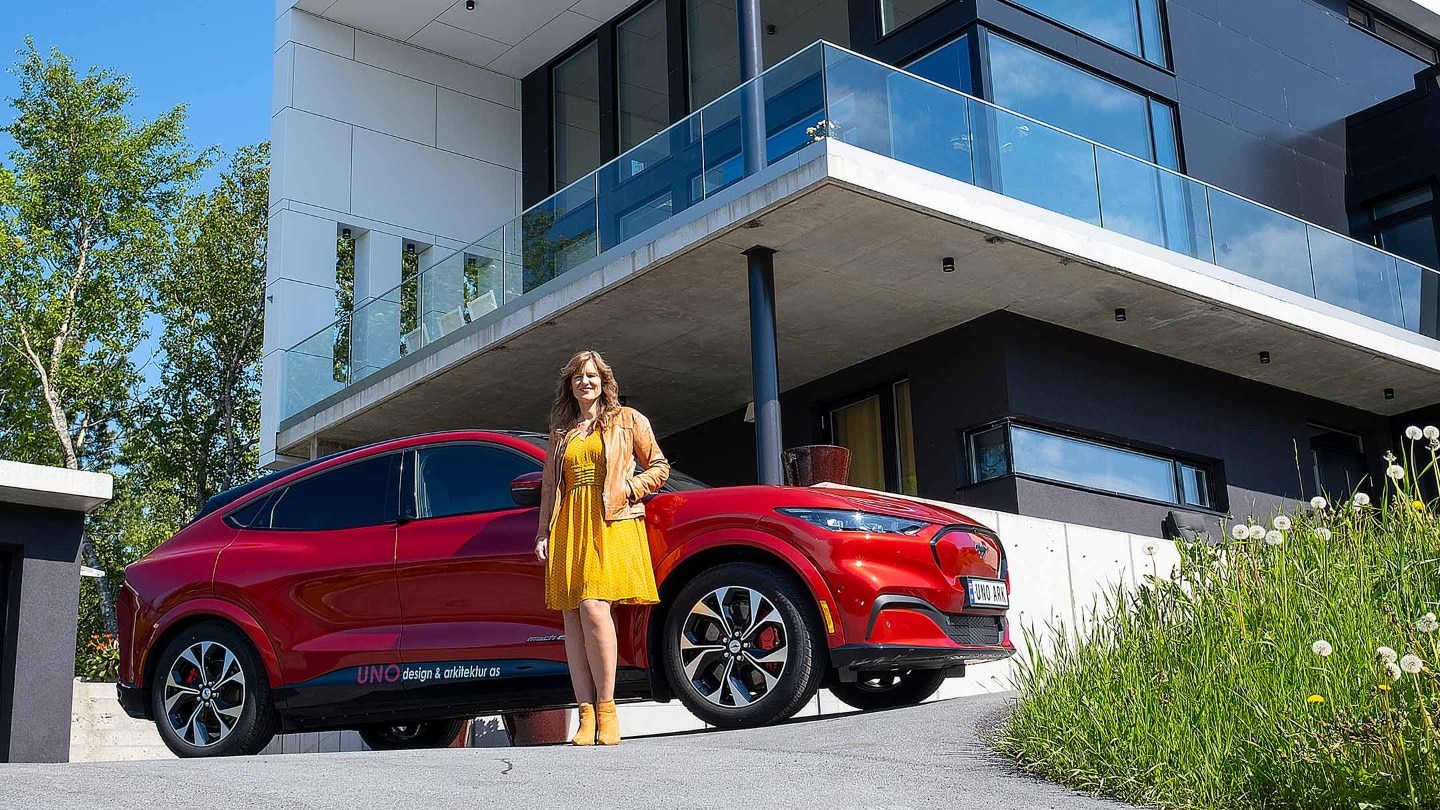 Lady in yellow dress standing next to the Mustang Mach-E