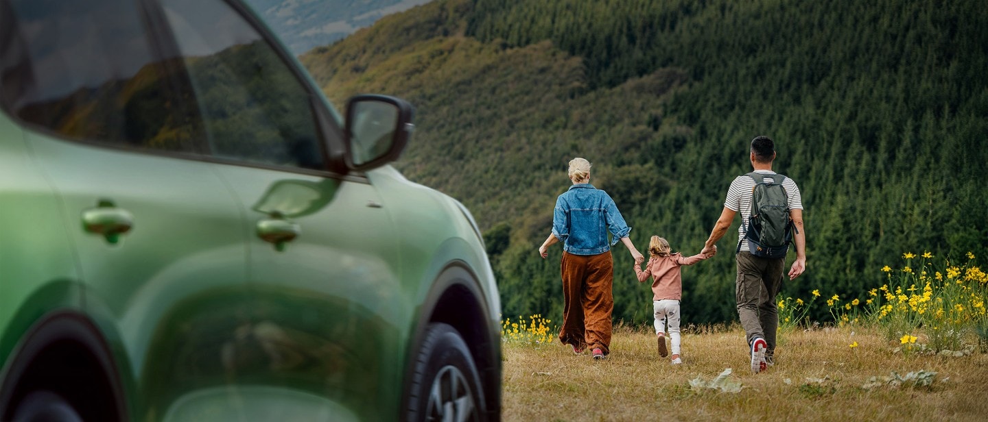 Familie på tur ved siden av en grønn Ford Kuga