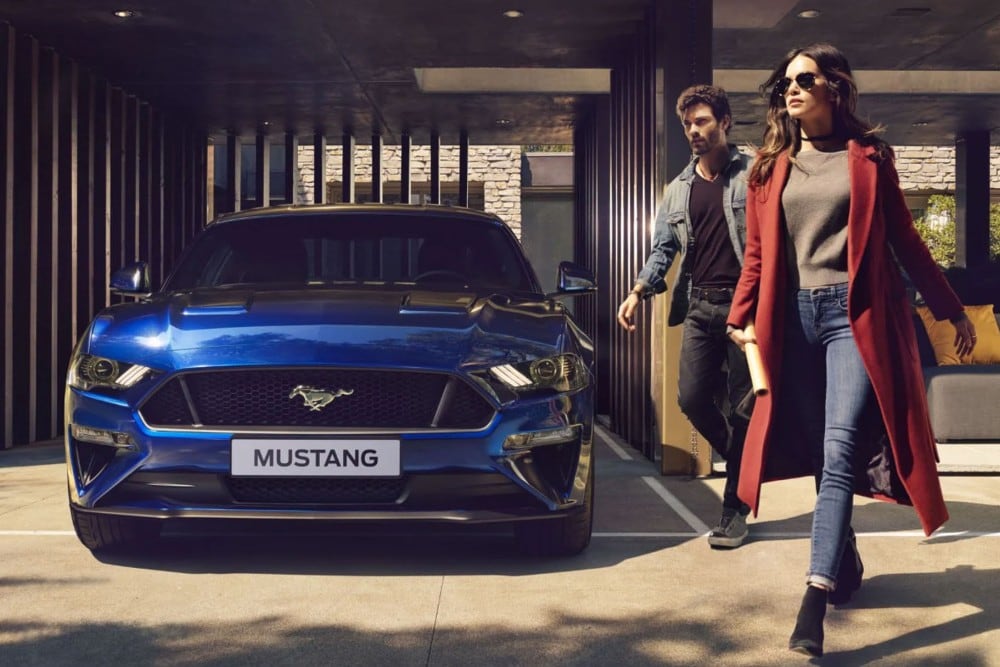 Blå Ford Mustang parkert foran huset