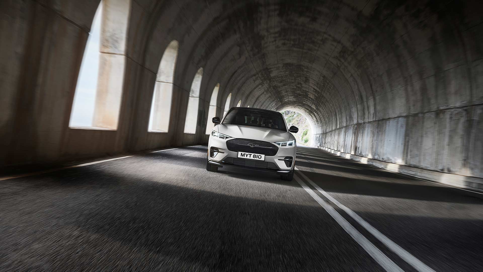  En sølvfarget Ford Mustang Mach-E kjøring gjennom en tunnel.
