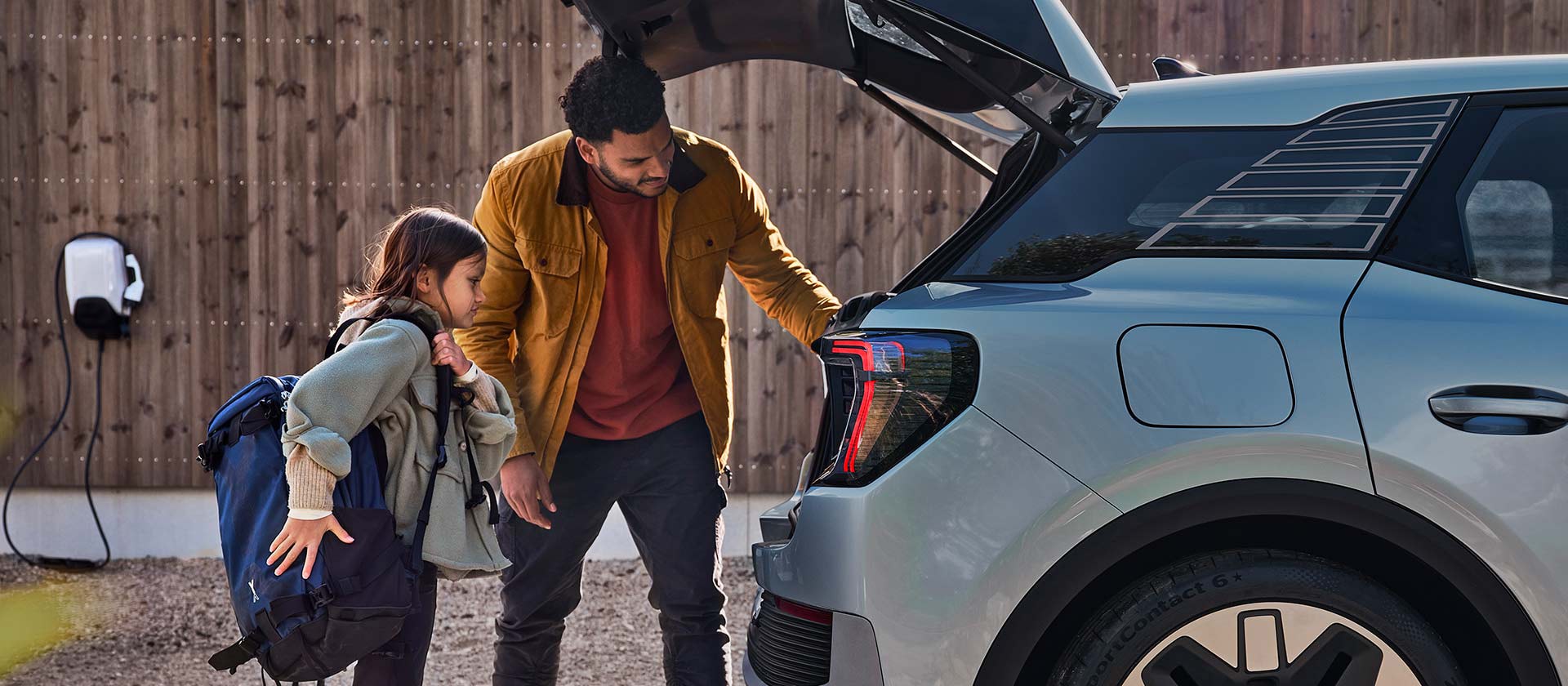  En familie som laster bagasjerommet til en blå helelektrisk Ford Explorer.