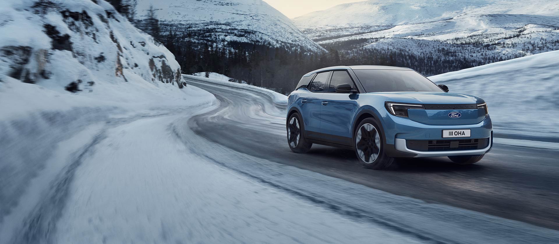  Blå helelektrisk Ford Explorer på snødekt fjellvei, noe som fremhever kapasiteten og rekkevidden om vinteren.