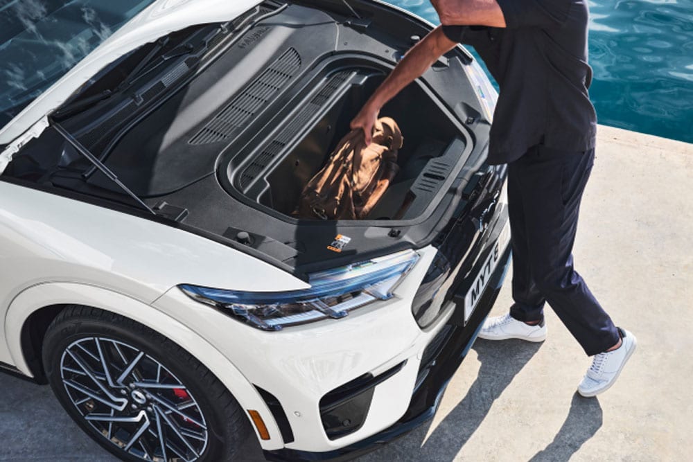 En person som legger en bag i en hvit frunken på  Ford Mustang Mach-E.
