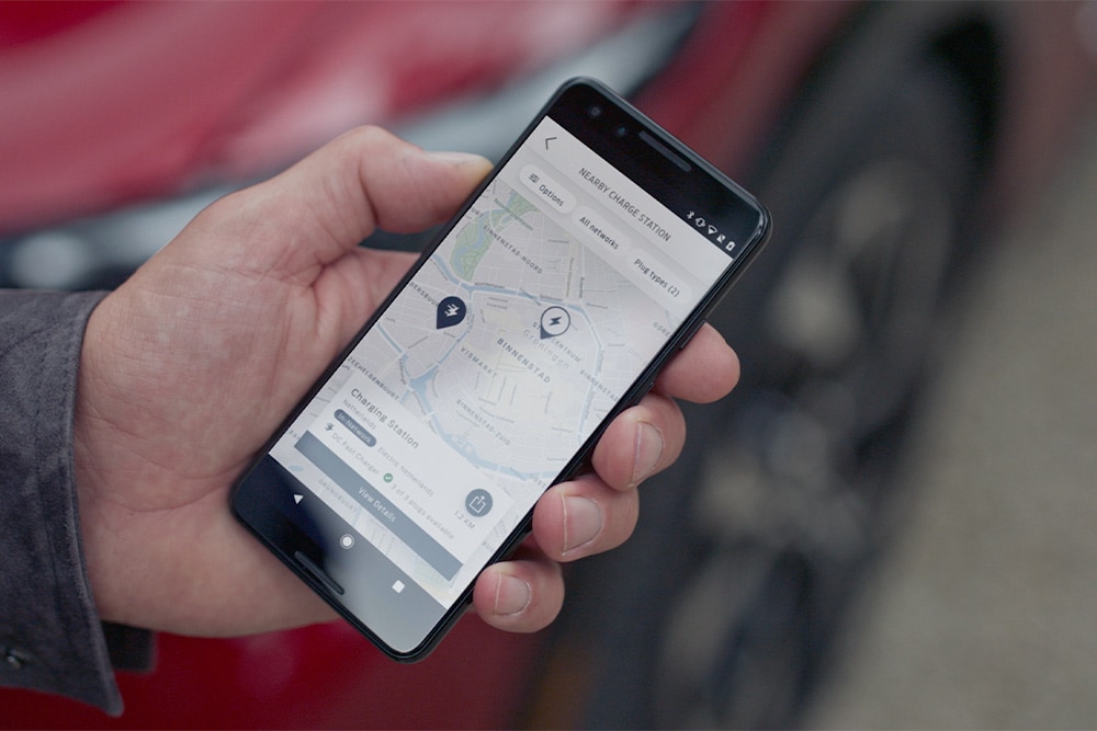  En smarttelefon som viser FordPass™-appen med ladepunkter i nærheten for offentlig lading.