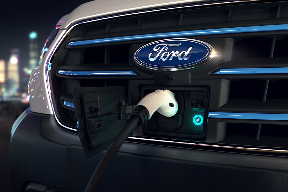  Nærbilde av en Ford E-Transit ladepunkt og blått ovalt Ford-merke på frontgrillen.