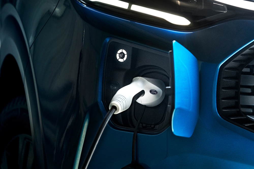 Et nærbilde av en elektrisk ladekabel koblet til en Ford E-Transit Custom elektrisk varebil.