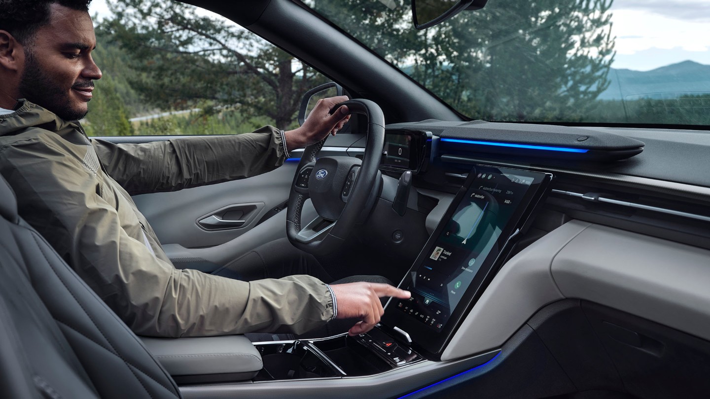 En mann som sitter i førersetet på Ford Explorer, og samhandler med den store SYNC-touchskjermen.