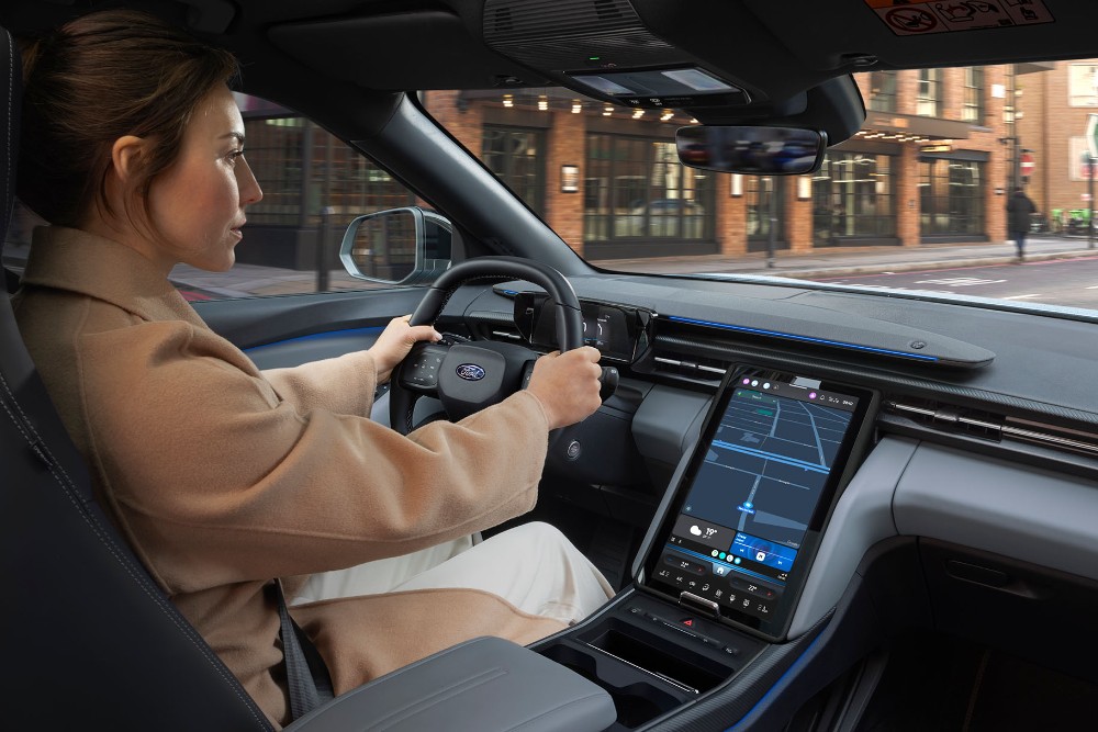 Et interiørbilde av en kvinne som kjører Ford Explorer langs en byvei.