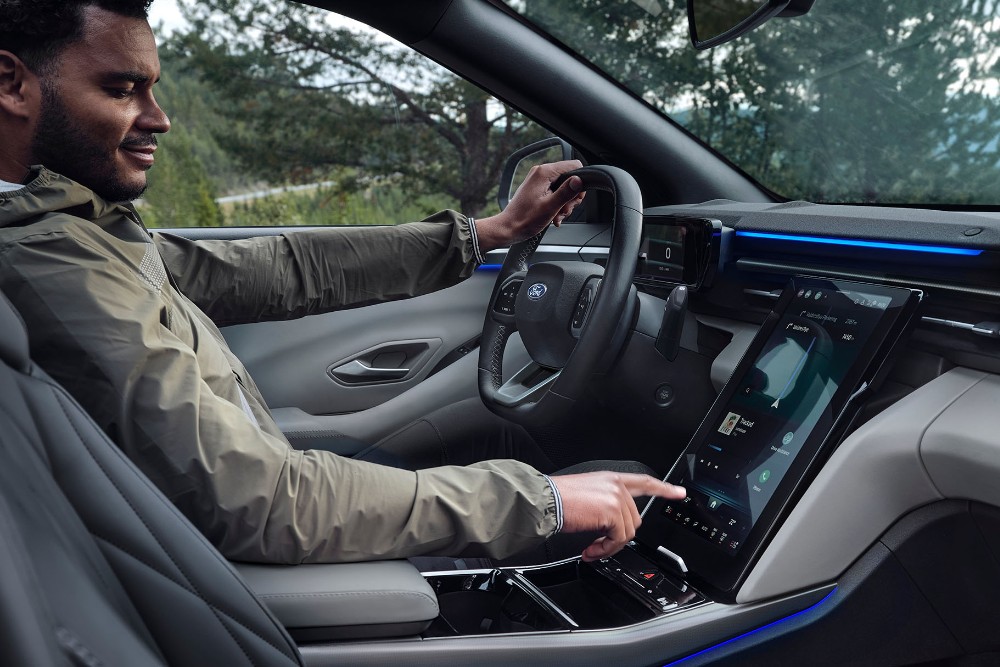 En mann som sitter i førersetet på Ford Explorer, og samhandler med den store SYNC-touchskjermen.