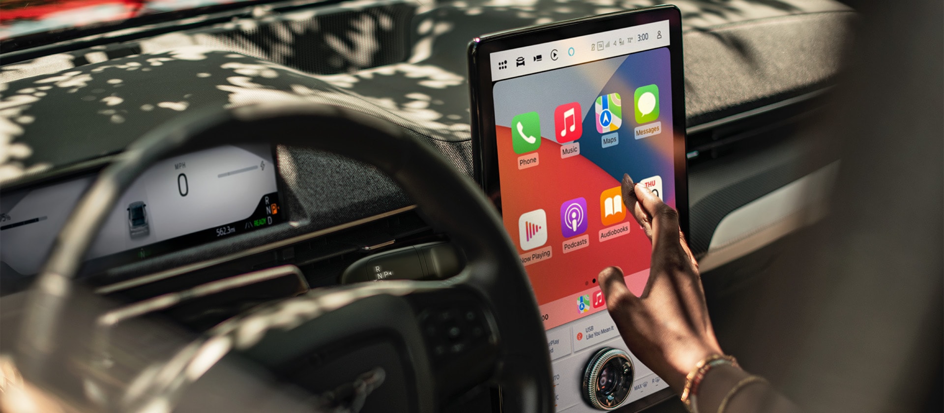 Et nærbilde av føreren av en Ford Mustang Mach-E, som samhandler med den store 15,5-tommers SYNC 4-touchskjermen som viser Apple CarPlay. 