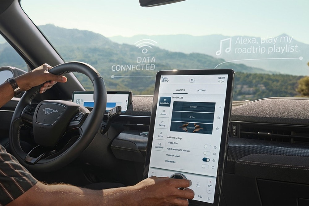 Nærbilde av sjåføren i en Ford Mustang Mach-E som trykker på den 15,5'' store SYNC 4 touchskjermen.
