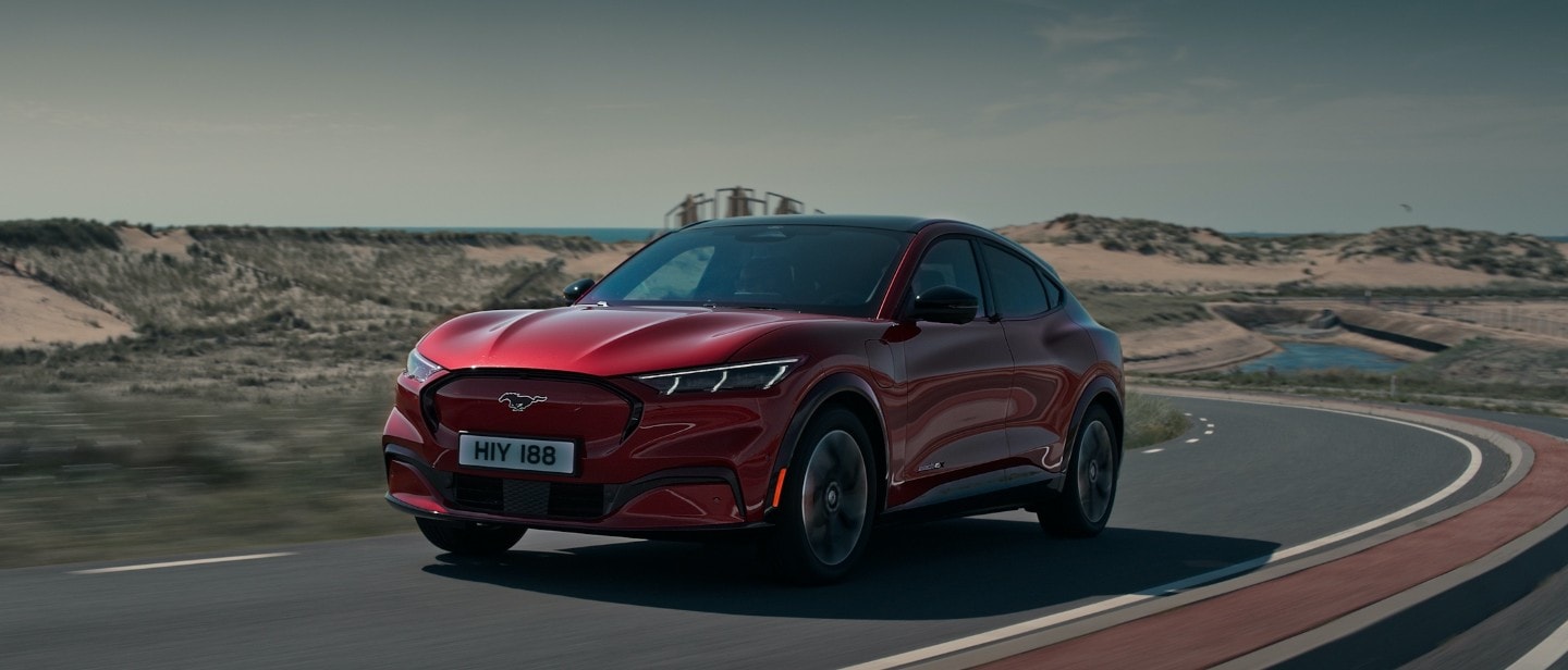 All-New red Ford Mustang Mach-E driving on a road All-New red Ford Mustang Mach-E driving on a road