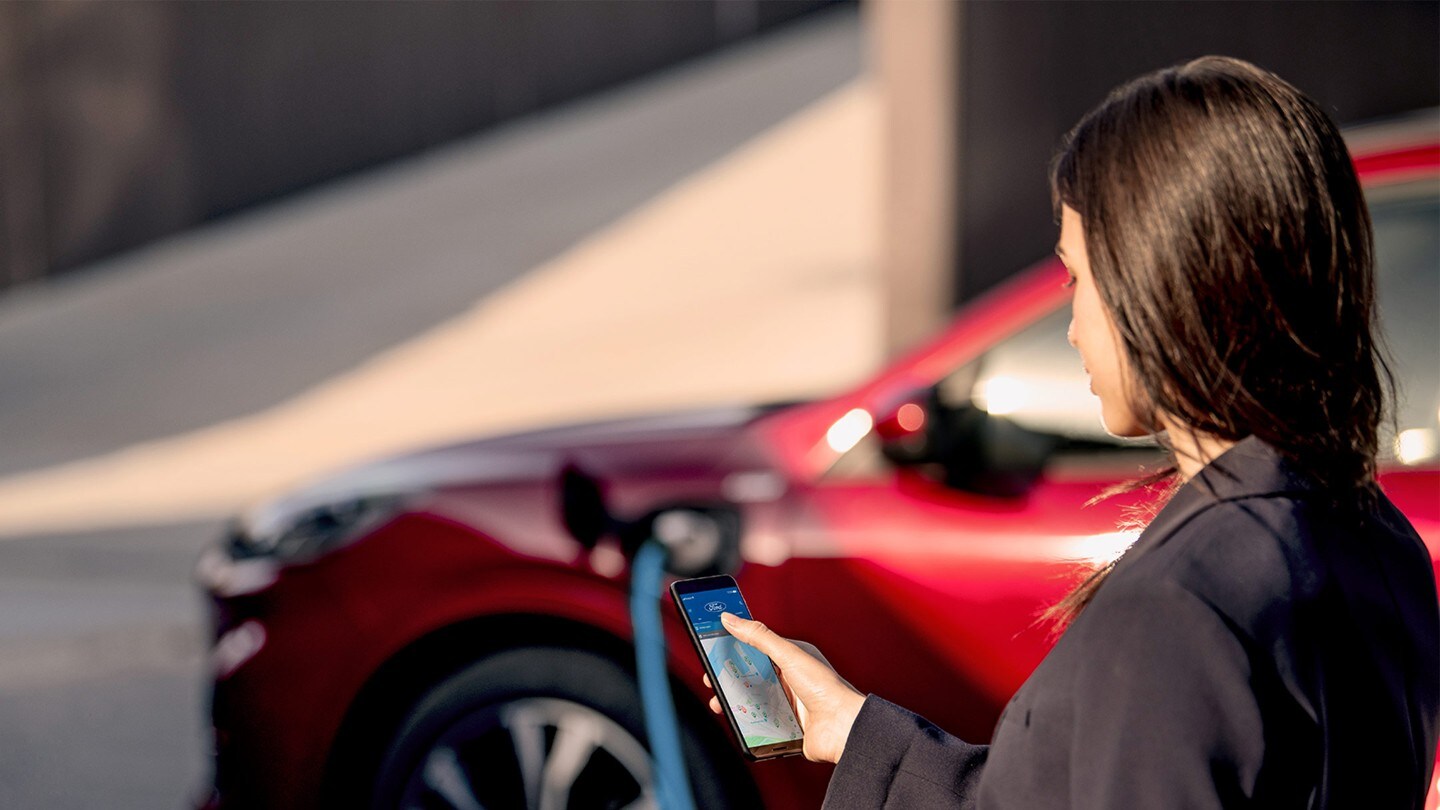 Woman checking her phone whilst charging Ford Kuga