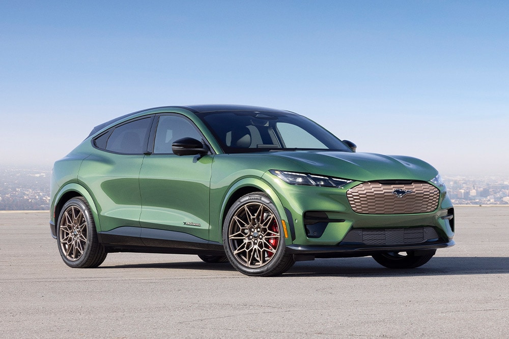 En grønn Ford Mustang Mach-E parkert foran en bysilhuett.