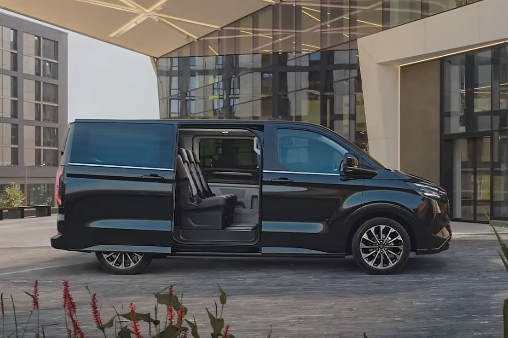 En svart Ford E-Tourneo Custom står parkert med sidedøren åpen, slik at de innvendige setene kommer til syne.