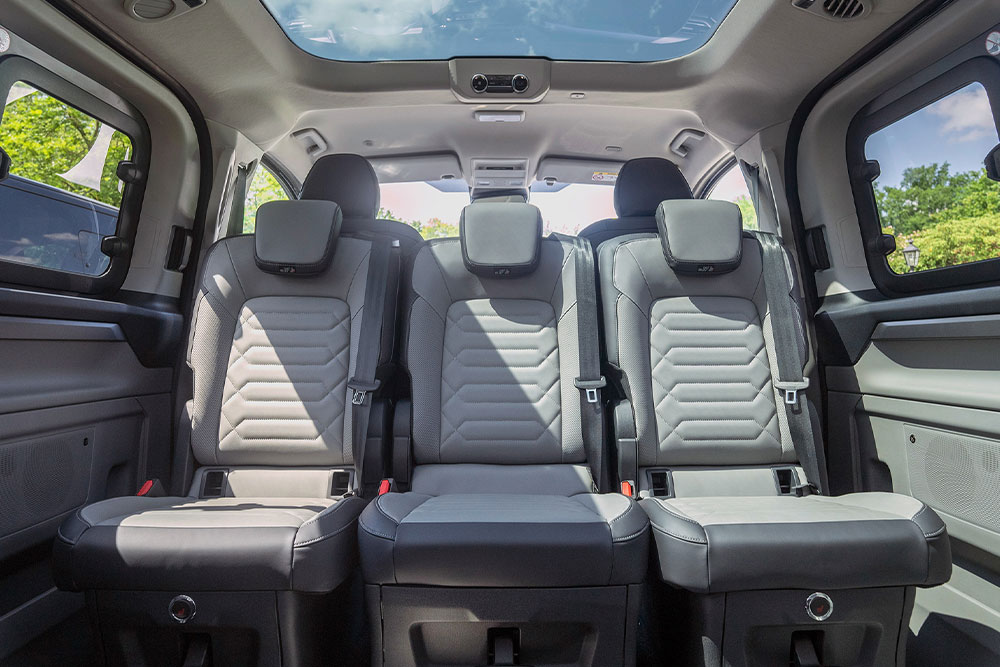 Interiørvisning av et kjøretøy, som viser de grå baksetene og et soltak.