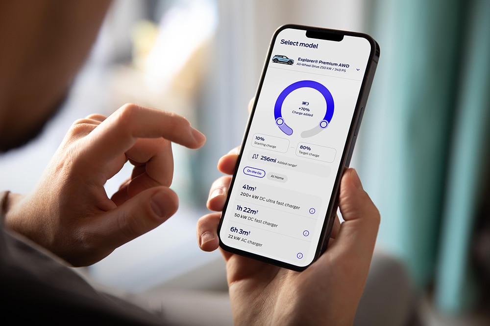 A person holding a smartphone displaying the Ford app with an EV charging progress interface.