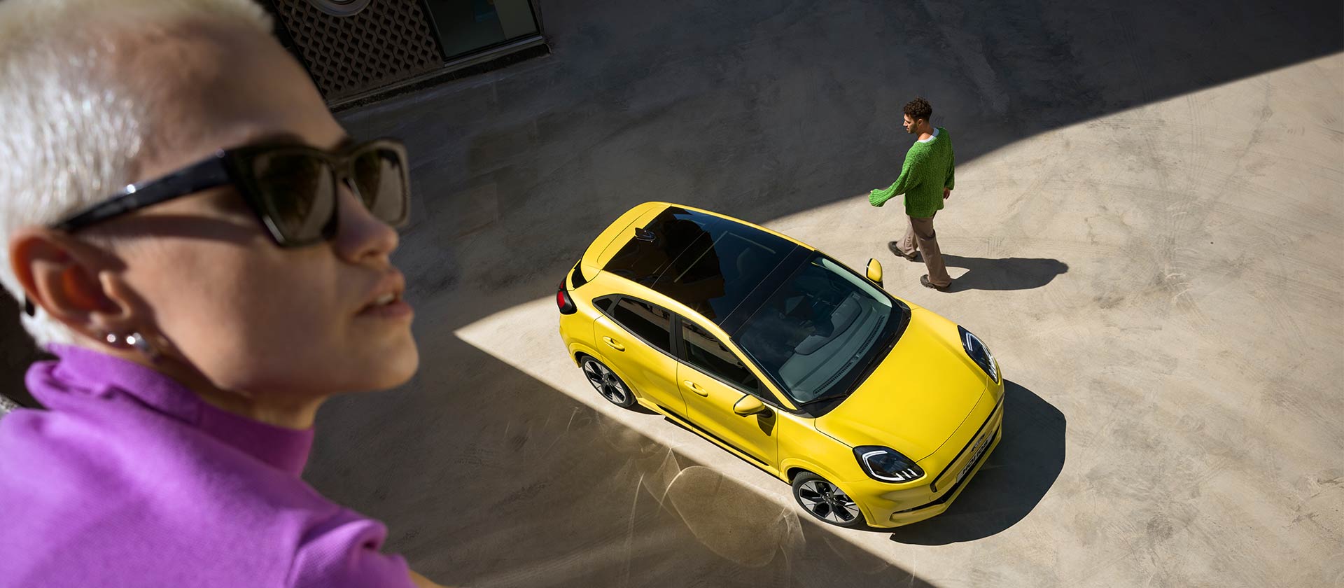 En gul elektrisk Ford Puma® i fugleperspektiv. Person kledd i lilla i forgrunnen.