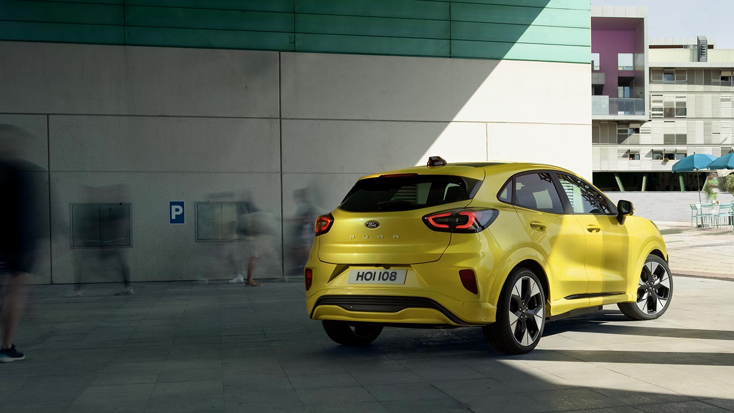 En gul elektrisk Ford Puma ® parkert under en bro vist bakfra.