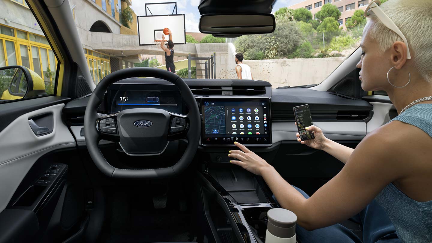 Interiøret i Ford Puma®, med en person som synkroniserer mobiltelefonen til den store touchskjermen trådløst.