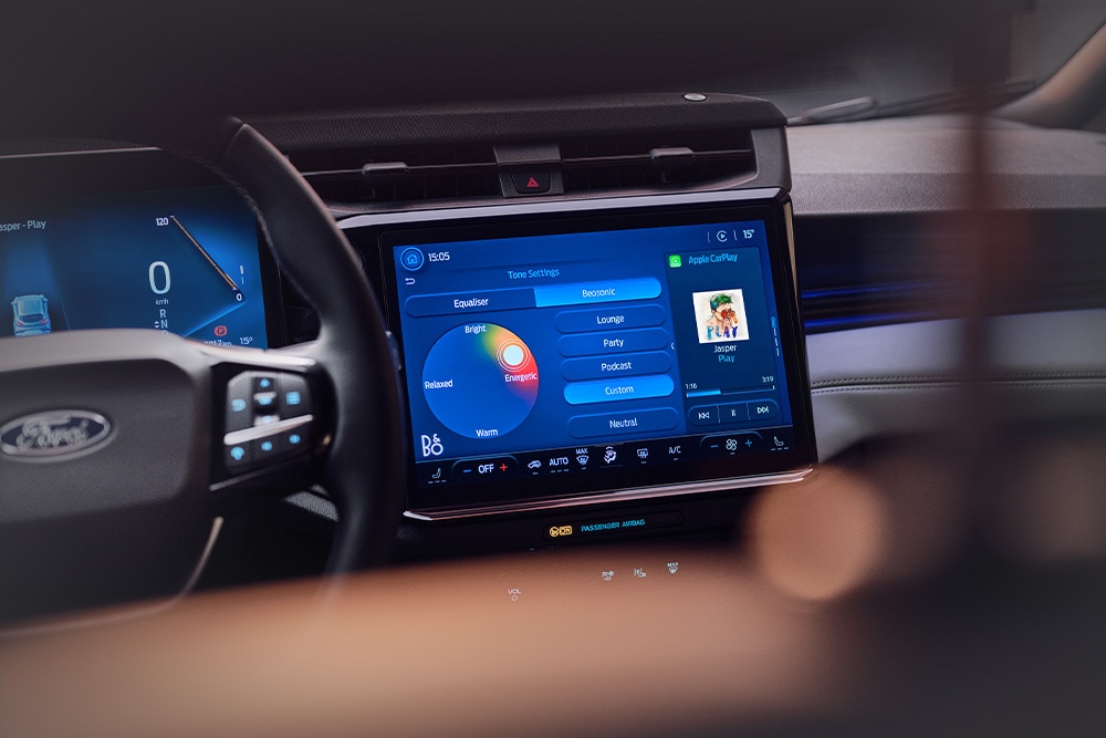 Nærbilde av et infotainmentsystem med stor touchskjerm, som viser B&O Beosonic-funksjonen i Ford Puma Sound Edition.