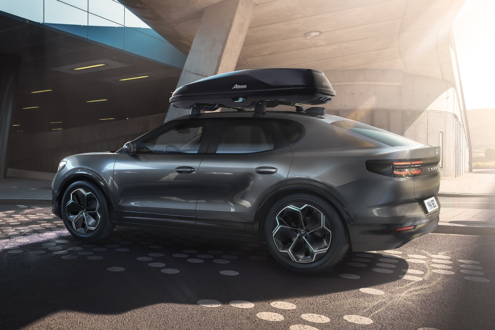 3/4 sidevisning av en rød Ford Capri med takboks, parkert under en moderne bygningsstruktur.