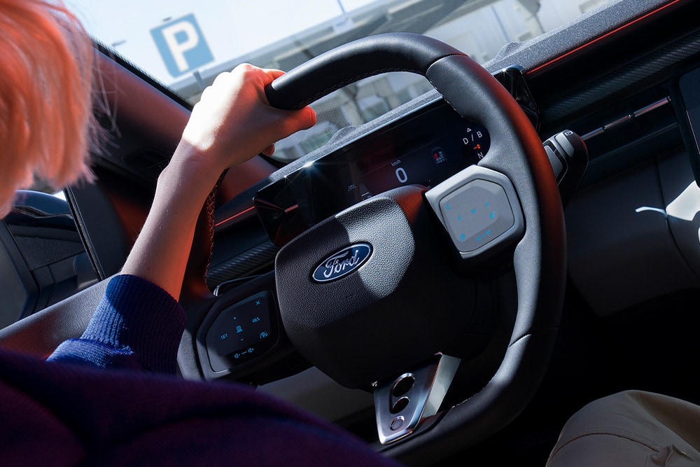 Et nærbilde av en kvinne som holder rattet i en parkert Ford Capri, og som også viser det digitale kombiinstrumentet.
