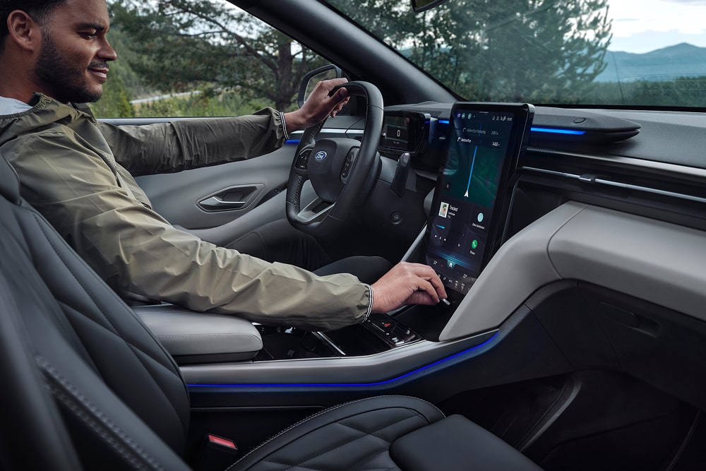 Fører som bruker berøringsskjermens infotainment-system på innsiden av en Ford Explorer-familie-SUV.