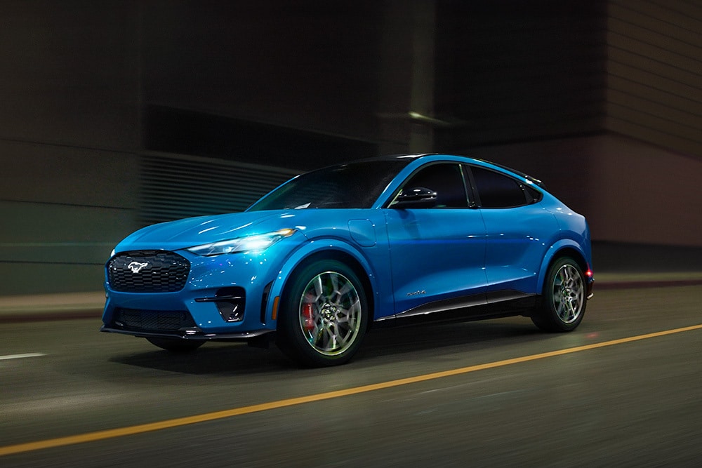 En blå Ford Mustang Mach-E GT elektrisk sportsbil som kjører på åpen vei.