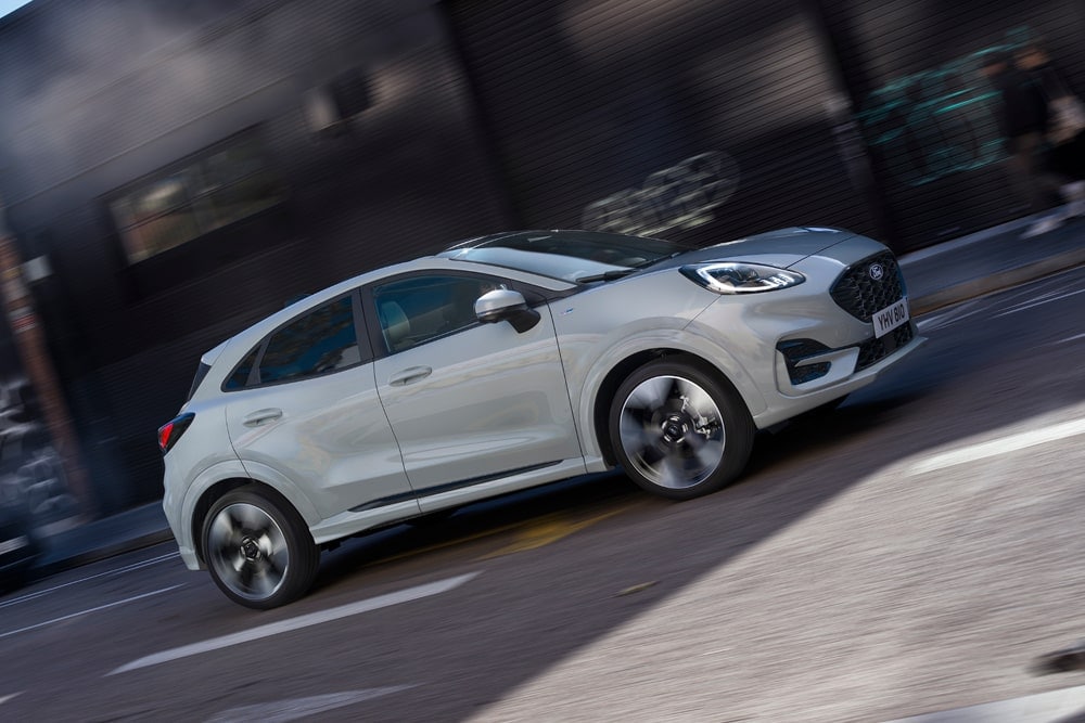 Sølvfarget Ford Puma fra utvalget av små Ford-biler kjørende langs en bygate.