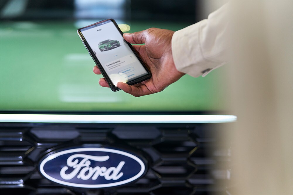 Mann som ser på en smarttelefon med Ford-appen oppe