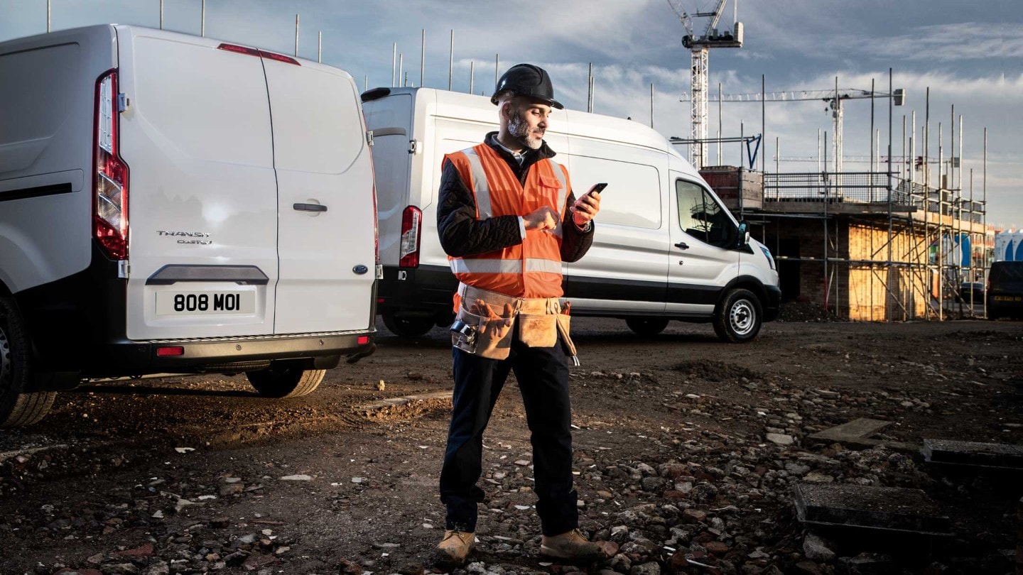 Man in high viz jacket checking his phone on building site