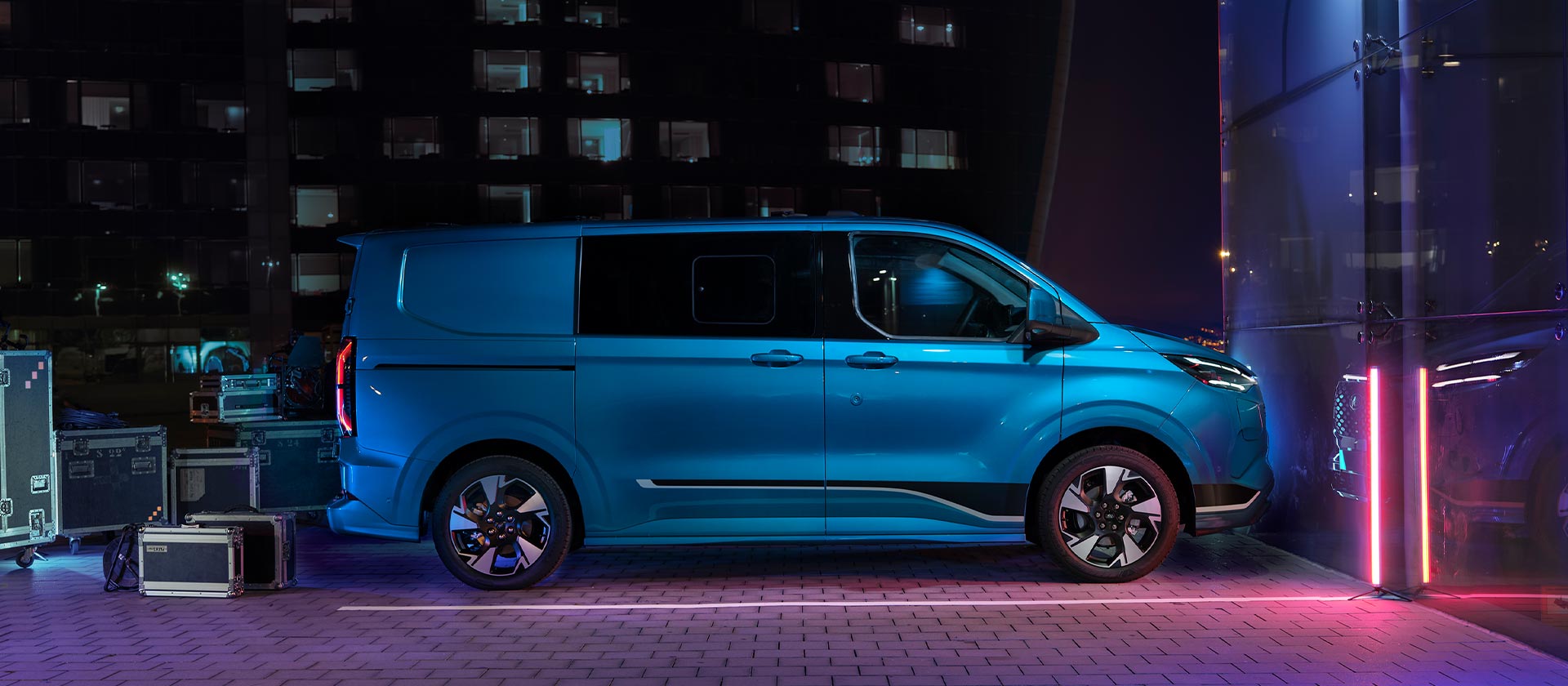 Blå elektrisk Ford E-Transit Custom-varebil, vist fra siden.