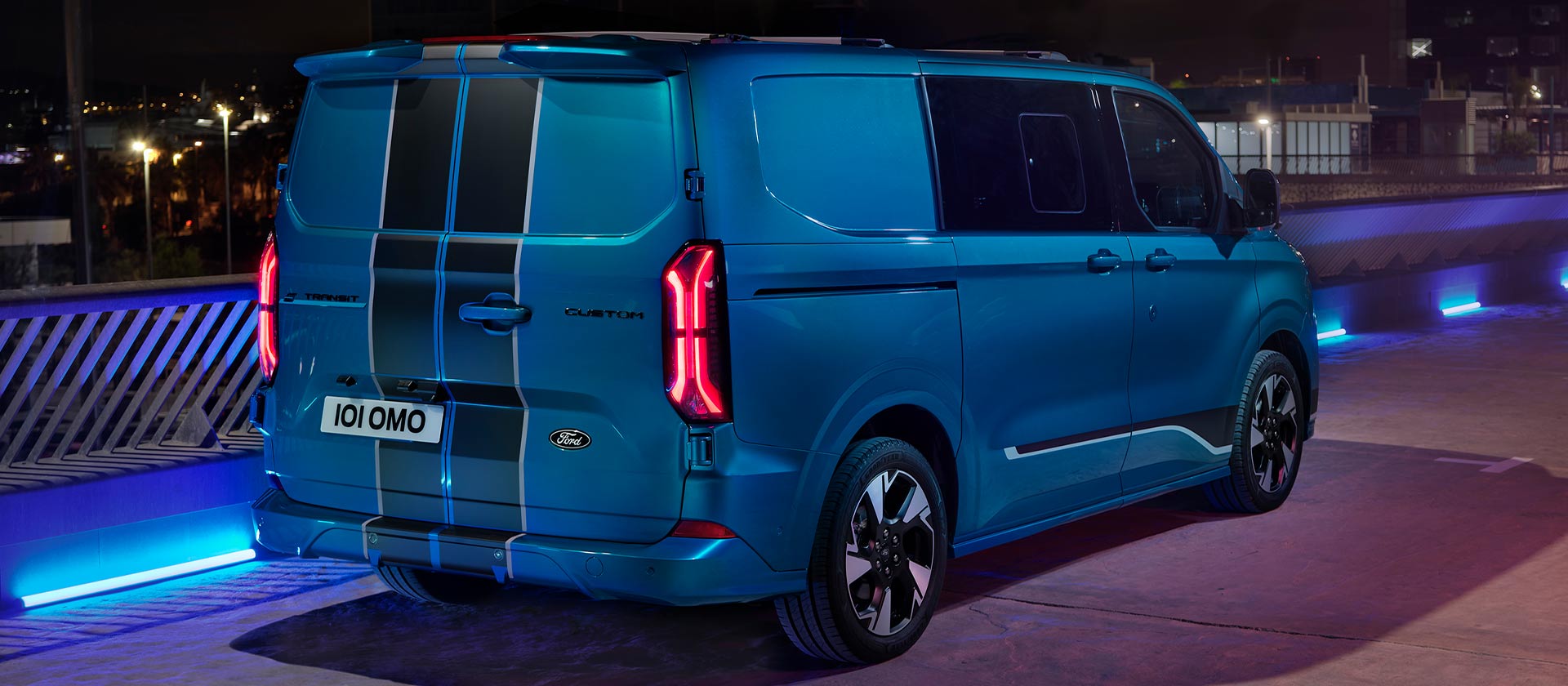 Blå elektrisk Ford E-Transit Custom Sport dobbelkabin varebil vist bakfra.