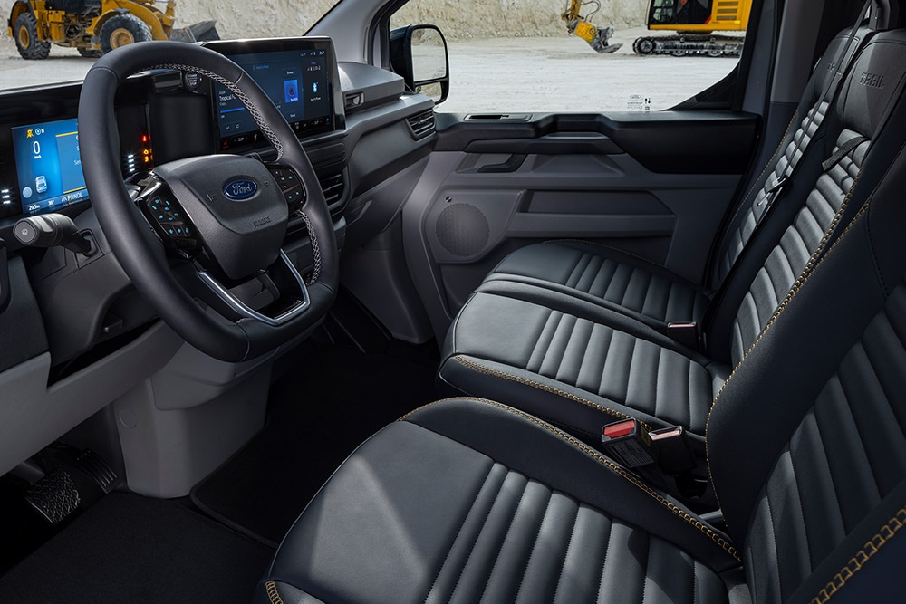 Interiør i en elektrisk Ford E-Transit Custom Sport-varebil med sorte og gullfargede seter.