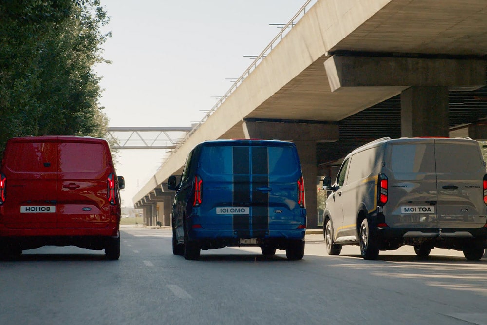 Tre Ford Transit Custom-varebiler som kjører på en motorvei.
