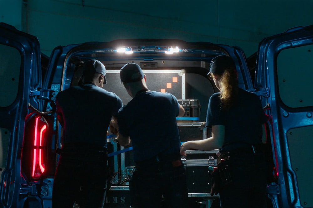 Tre personer som jobber bak i en Ford E-Transit Custom-varebil.