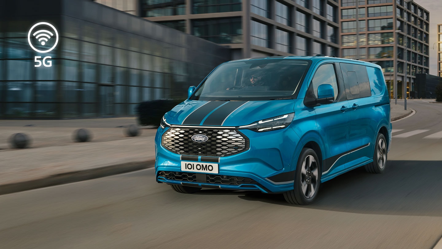 Blå elektrisk Ford E-Transit Custom-varebil som kjører på en bygate.