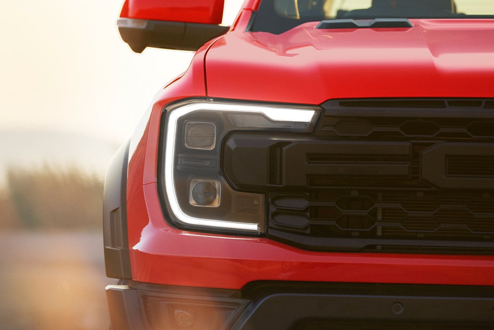  Nærbilde av en kode oransje Ford Ranger Raptor hovedlykt og grill.