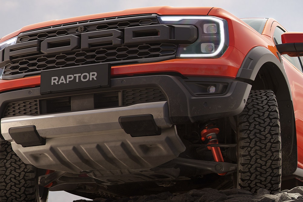 Undersiden foran på en kode oransje Ford Ranger Raptor som viser hjulopphenget og frontgrillen.