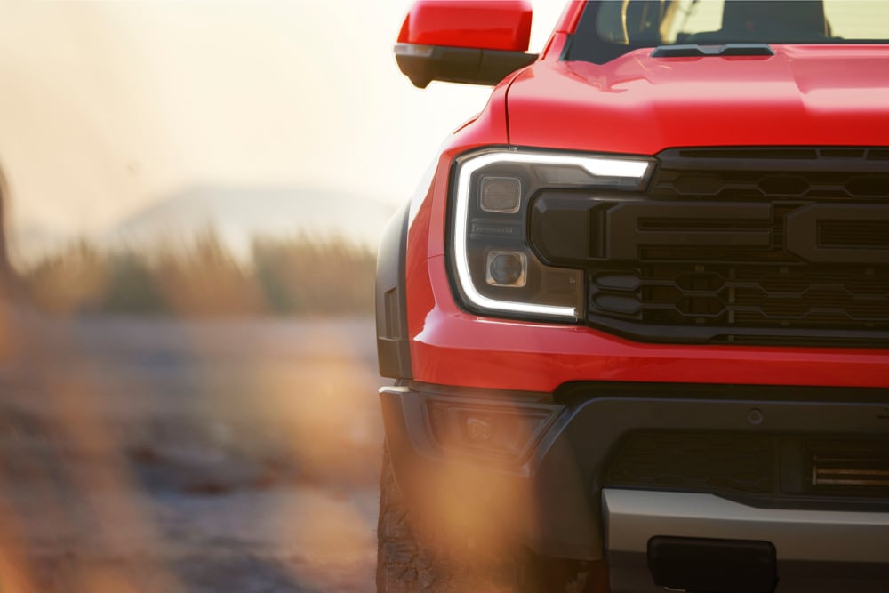 Nærbilde av frontgrillen på en rød Ford Ranger Raptor.
