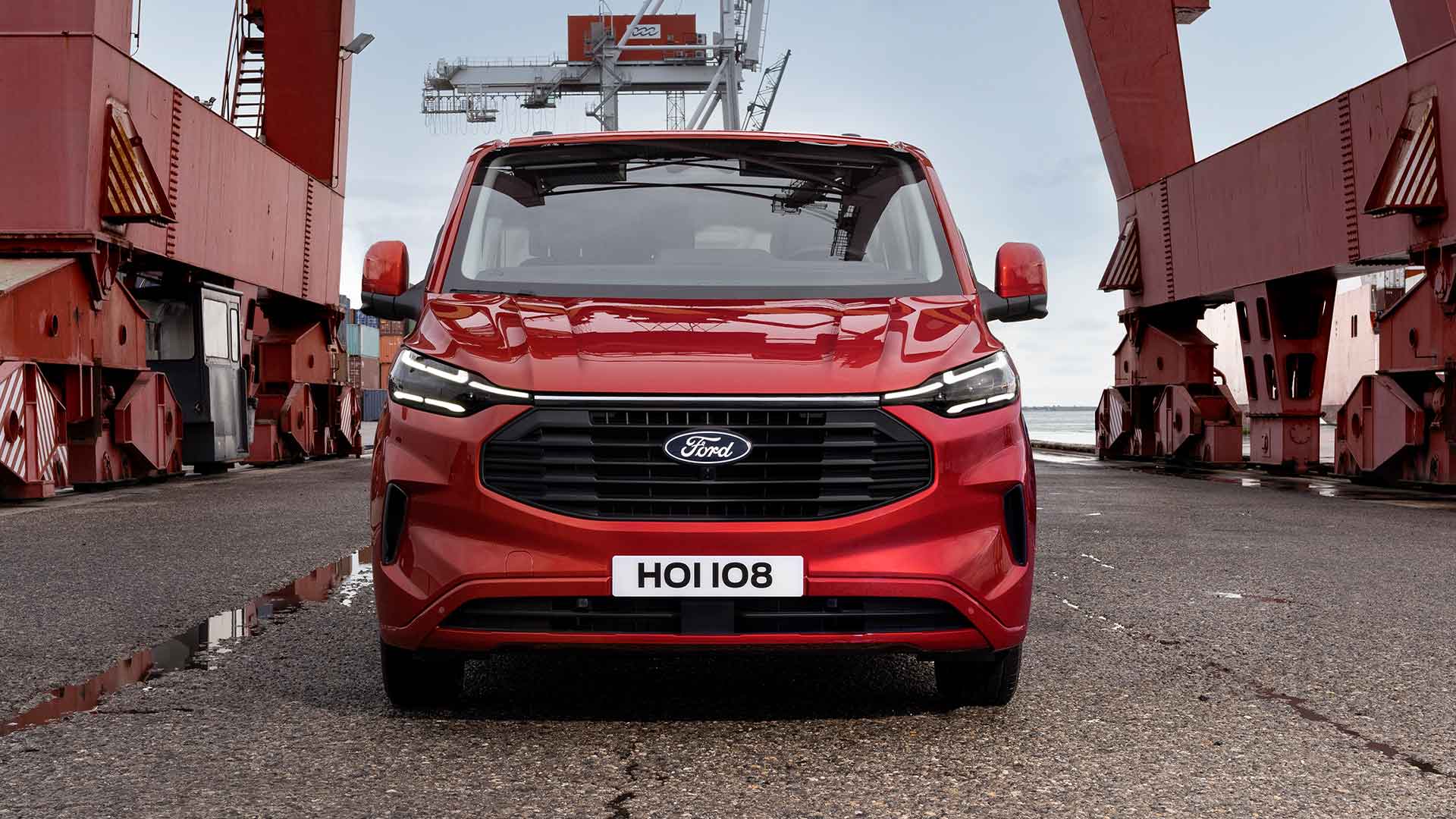 Rød Ford Transit Custom-varebil ved en havn.