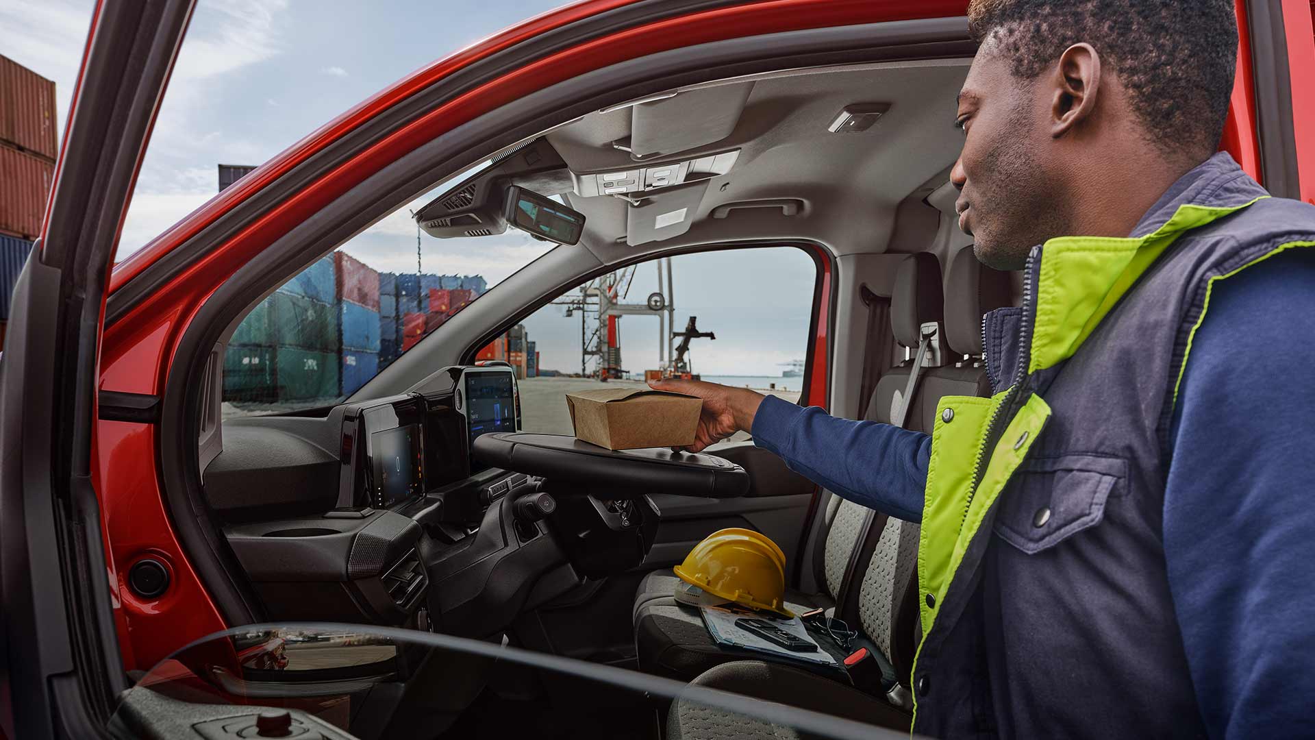 Person som plasserer en pakke i en rød Ford Transit Custom.