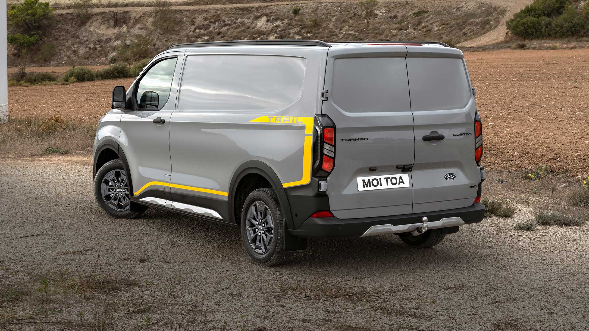 En grå Ford Transit Custom Trail-varebil vist bakfra.